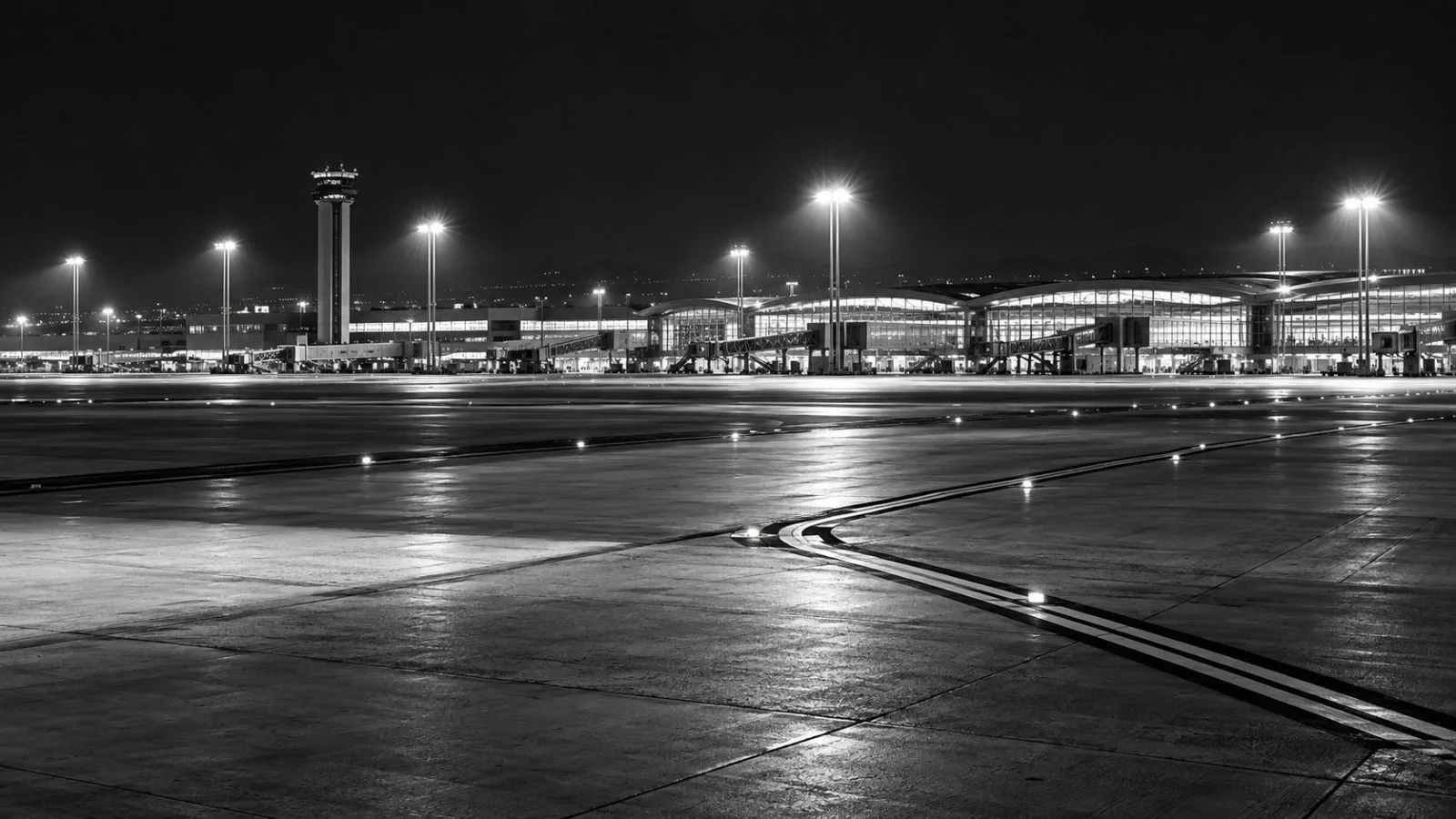 An empty taxiway stretches beside an airport terminal after dark / TokenPost.ai