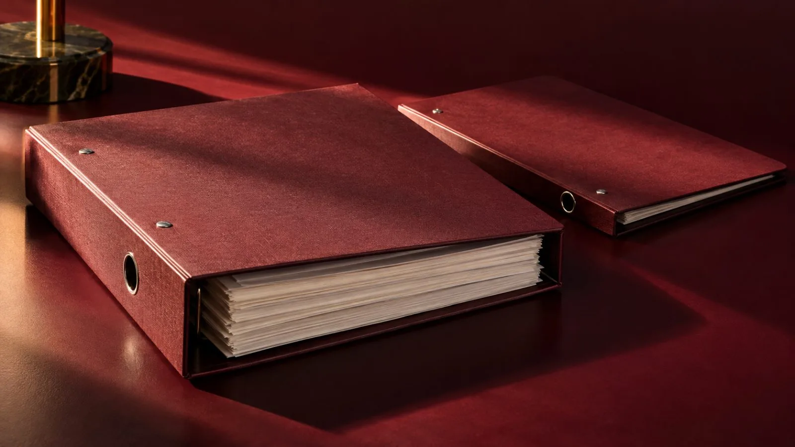 Two unmarked lending folders rest on a burgundy surface / TokenPost.ai