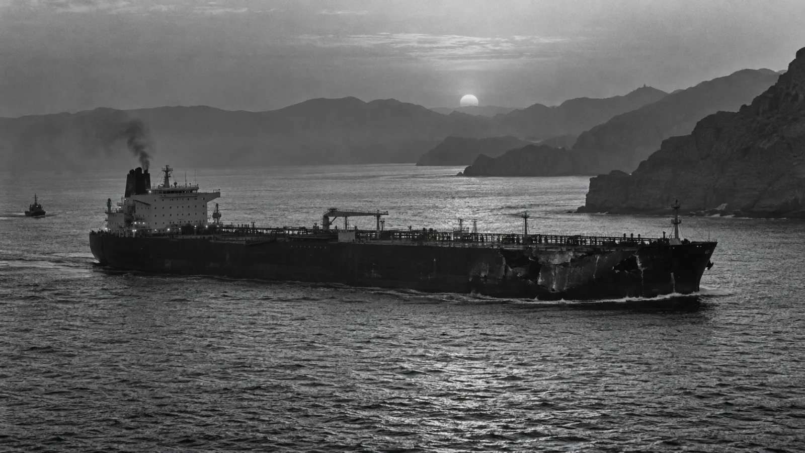 Damaged tanker moving through the strait beneath fading evening light / TokenPost.ai