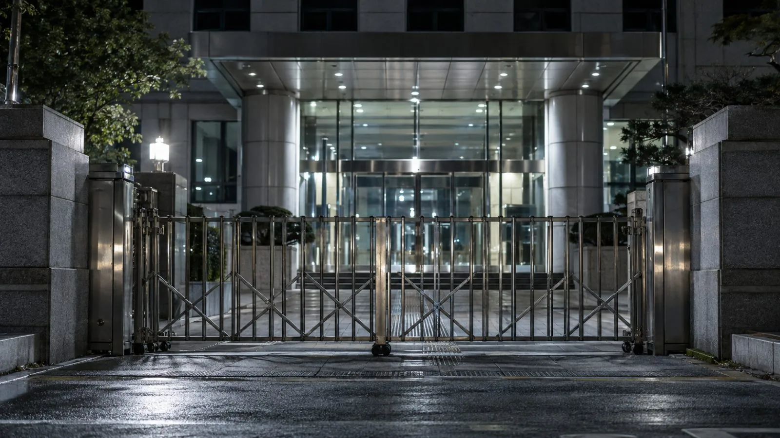 Glass doors and a closed security gate stand beneath white lights / TokenPost.ai