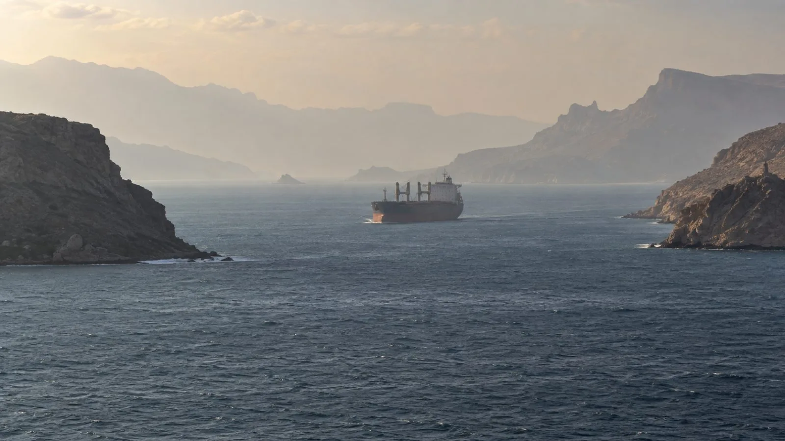 Cargo ship passing a narrow strait under hazy morning light / TokenPost.ai