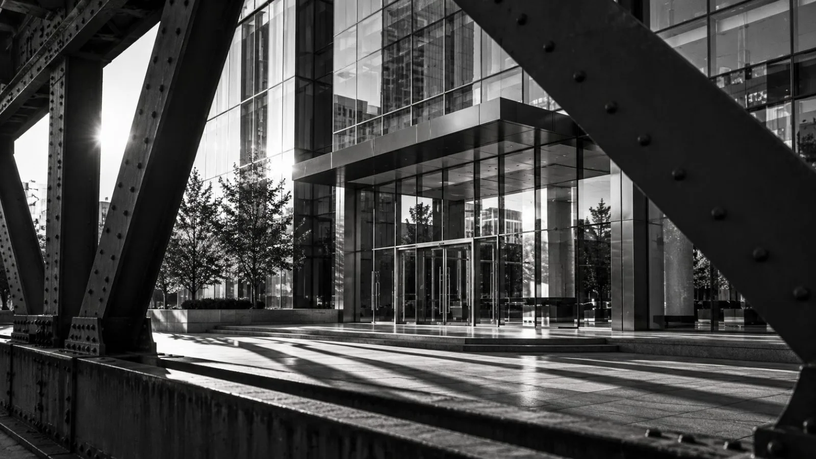 Glass office facade framed by red steel bridge beams / TokenPost.ai