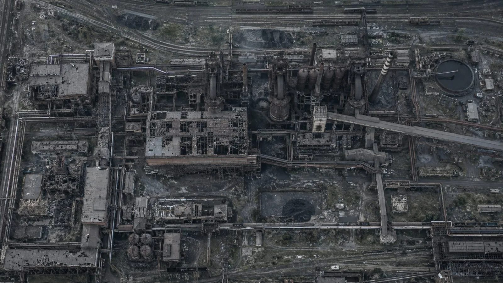Damaged steel mill stands idle beside empty rail tracks / TokenPost.ai